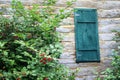 Wooden Teal Green door Window on a rough hewn log cabin side with a bush Royalty Free Stock Photo