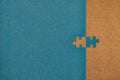 Teal jigsaw puzzle with one missing piece placed on the side over a brown background Royalty Free Stock Photo