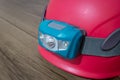 Teal led headlamp turned off strapped to a pink climbing helmet on a wooden table Royalty Free Stock Photo