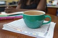 A teal mug of coffee sits atop a stack of papers, subtly reflecting the text. The blurred background suggests a busy workspace, Royalty Free Stock Photo