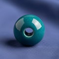 A teal spherical ceramic bead with a central hole is placed on a soft blue Royalty Free Stock Photo