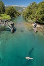 Teal green river water in Patagonia, Argentina with old bridge and girl swimming Royalty Free Stock Photo