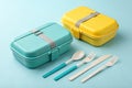 Teal and Yellow Lunchboxes with Utensils on Light Blue Background - generated by ai Royalty Free Stock Photo