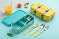 Teal and Yellow Lunchboxes with Utensils on Light Blue Background - generated by ai Royalty Free Stock Photo