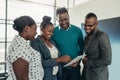 Team of african business people standing and smiling and laughing while using a tablet Royalty Free Stock Photo