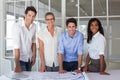 Team of architects going over blueprints smiling at camera Royalty Free Stock Photo