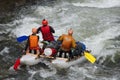 Team of athletes on an inflatable catamaran rafting on white water.