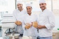 Team of bakers smiling at camera holding bread Royalty Free Stock Photo