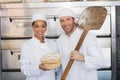 Team of bakers smiling at camera with loaf Royalty Free Stock Photo