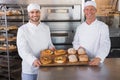 Team of bakers smiling at camera with trays of bread Royalty Free Stock Photo
