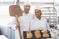 Team of bakers smiling at camera with trays of loaves Royalty Free Stock Photo