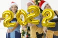 Team of builders holds numbers 2022 against backdrop of New Year tree