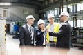 Team of business people examining machine part in metal industry