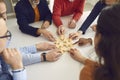 Team of business people sitting around office table and joining jigsaw puzzle pieces Royalty Free Stock Photo