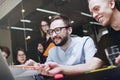 Team of cheerful colleagues works on modern gadgets. Crew of coworkers making work meeting in loft office