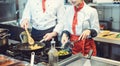 Team of chefs in a kitchen preparing fantastic food in pans