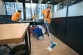 Team of cleaners work in coworking area, women clean all surfaces Royalty Free Stock Photo