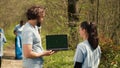 Team of climate and nature activists using laptop with greenscreen near a forest