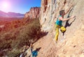 Team of Climbers Man and Woman ascending orange bright rocky Wall with rope and gear Royalty Free Stock Photo