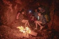 Team of climbers man and woman hiker camping.They are sitting around fire camp in the cave.