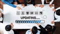 Team Collaboration in a Modern Workspace During an Update, Showing Various Icons and Progress Bar on a Table with Royalty Free Stock Photo