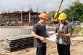 Team of construction workers discussing project details with blueprint in construction site Royalty Free Stock Photo