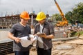 Team of construction workers discussing project details with blueprint in construction site Royalty Free Stock Photo