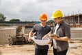 Team of construction workers discussing project details with blueprint in construction site Royalty Free Stock Photo