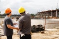 Team of construction workers discussing project details with blueprint in construction site Royalty Free Stock Photo