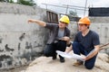 Team of construction workers discussing project details with blueprint in construction site Royalty Free Stock Photo
