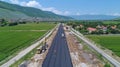 Team of construction workers laying tarmac on road construction site, leveling asphalt gravel