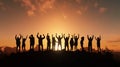 A team of coworkers celebrate their collective success, silhouettes cast against a golden sunset