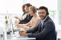 Team of customer service agents with headsets working at computers in office, empty space Royalty Free Stock Photo