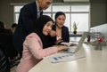 Team at desk working together with laptop in open plan business space office Royalty Free Stock Photo