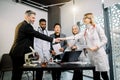 Team of doctors, scientists, pharmaceutical workers having meeting in modern lab with equipment. Caucasian man and woman