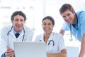 Team of doctors working on laptop and smiling at camera Royalty Free Stock Photo