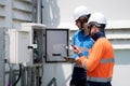 Team engineer inspect electrical control panel using tablet checking voltage, system connection and industrial infrastructure, Royalty Free Stock Photo