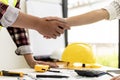 A team of engineers and architects shake hands after co-designing a house for a client. Royalty Free Stock Photo