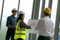 Team of Engineers architects working and standing around table working on blueprint at construction plans. Engineers discussing