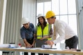 Team of Engineers architects working and standing around table working on blueprint at construction plans. Engineers discussing