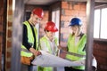 Team of engineers in vests and hard hats with schematics on a construction site Royalty Free Stock Photo