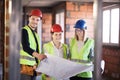 Team of engineers in vests and hard hats with schematics on a construction site