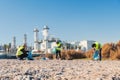 Team of environmental volunteer activist picking up plastic trash of the sand on the beach near a factory. Group of Royalty Free Stock Photo