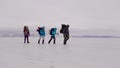Team of extremal travelers are walking over snow in winter day, hiking in the mountains, four people