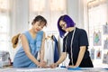 Team of fashionable freelance dressmakers making adjustment on muslin for new custom made dress while working in the artistic Royalty Free Stock Photo