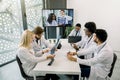 Team of five diverse multiethnic doctors having video conference meeting in hospital, chatting with their two young Royalty Free Stock Photo