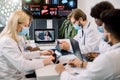 Team of five multiethnical doctors in protective masks, having video conference meeting in hospital with their young Royalty Free Stock Photo