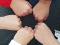 team of five women colliding their fists in agreement sign