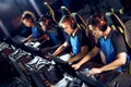 Team of focused professional cybersport gamers wearing headphones playing online video games while sitting in gaming
