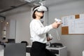 Team of four creative engineers working with virtual reality, young woman testing VR glasses or goggles sitting in the office room